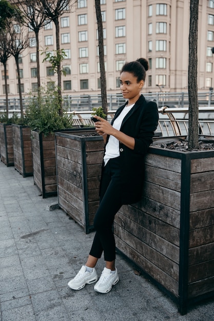 A woman wearing an oversized blazer over a simple dress, paired with sneakers for a casual yet chic look. The photo focuses on the proportions and how the oversized piece complements the overall outfit.