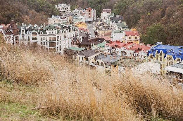 A picturesque scene from Petite France in Gapyeong, South Korea, with colorful buildings reminiscent of a French village. Actors dressed in period costumes are performing a street show. The audience is smiling and taking pictures, capturing the whimsical and romantic atmosphere of this popular filming location.