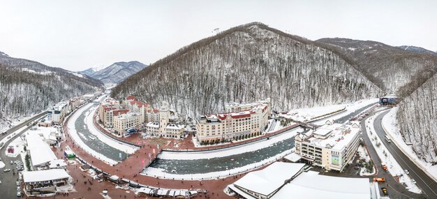 A panoramic view of Yongpyong Resort in Pyeongchang, South Korea, covered in a blanket of snow. Skiers are descending the slopes, and snow-covered trees line the landscape. The clear blue sky enhances the winter wonderland effect, showcasing the resort's popularity as a filming location, especially for winter-themed dramas.